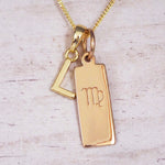 Gold Virgo initial necklace with a letter L pendant and zodiac bar on whitewashed wood