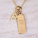 Gold Virgo initial necklace with a letter P pendant and zodiac bar on whitewashed wood