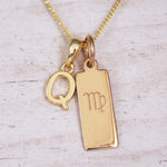 Gold Virgo initial necklace with a letter Q pendant and zodiac bar on whitewashed wood