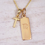 Gold Virgo initial necklace with a letter T pendant and zodiac bar on whitewashed wood