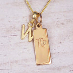 Gold Virgo initial necklace with a letter W pendant and zodiac bar on whitewashed wood