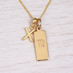 Gold Virgo initial necklace with a letter X pendant and zodiac bar on whitewashed wood
