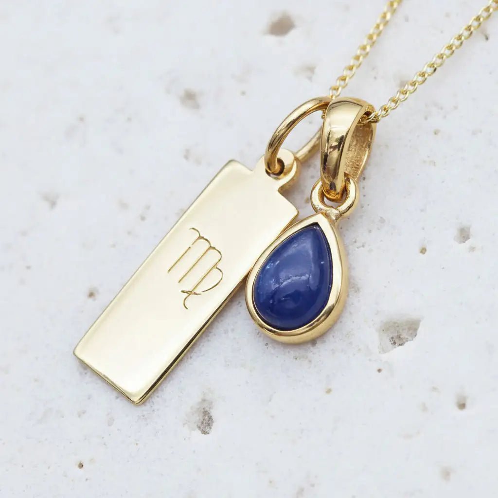 Gold September birthstone necklace with natural sapphire gemstone and virgo zodiac pendant on a textured background