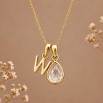 Gold initial W necklace with an April clear quartz teardrop on brown with dried flowers