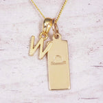 Gold initial and Libra zodiac necklace with a letter W charm and engraved bar pendant on whitewashed wood