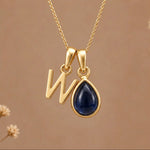 Gold Initial W Pendant and September birthstone Natural Sapphire Necklace against a warm background