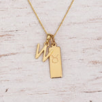 Gold W Initial and Taurus Necklace on a fine gold chain against a light wooden background