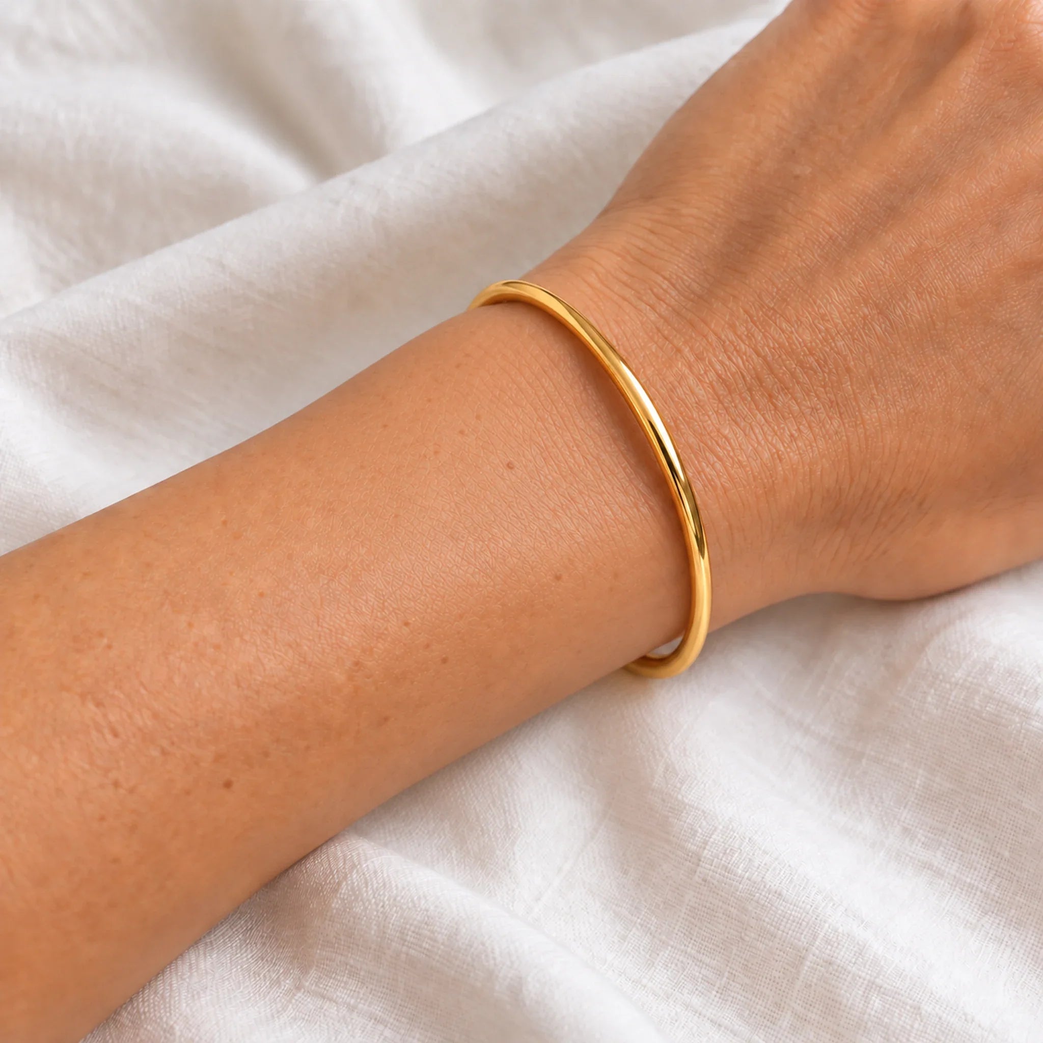 4 mm gold waterproof classic bangle bracelet worn on a wrist, 61 mm diameter, 18k gold plated stainless steel