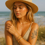 Woman on a beach wearing gold waterproof bangle bracelets