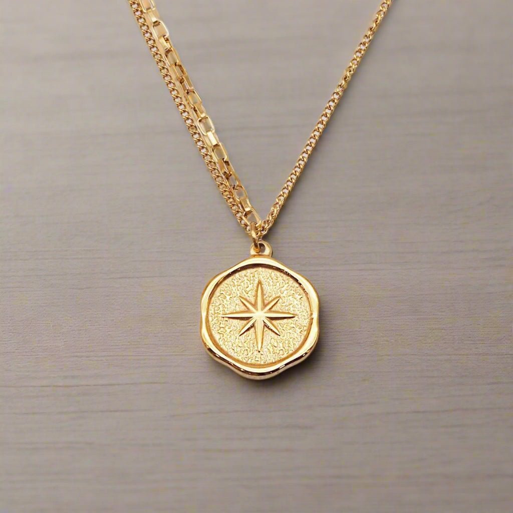 Gold Stainless Steel Starburst Pendant Waterproof Necklace with a light wooden background