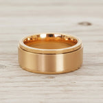 waterproof gold spinner Ring in minimalist stainless steel band design on a light wooden surface