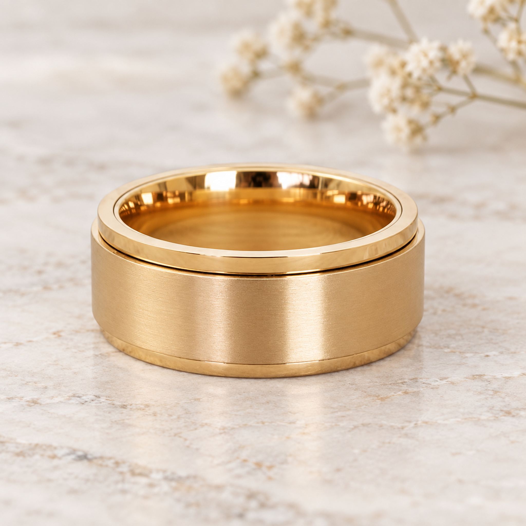 waterproof gold spinner Ring in minimalist stainless steel band design on a light wooden surface