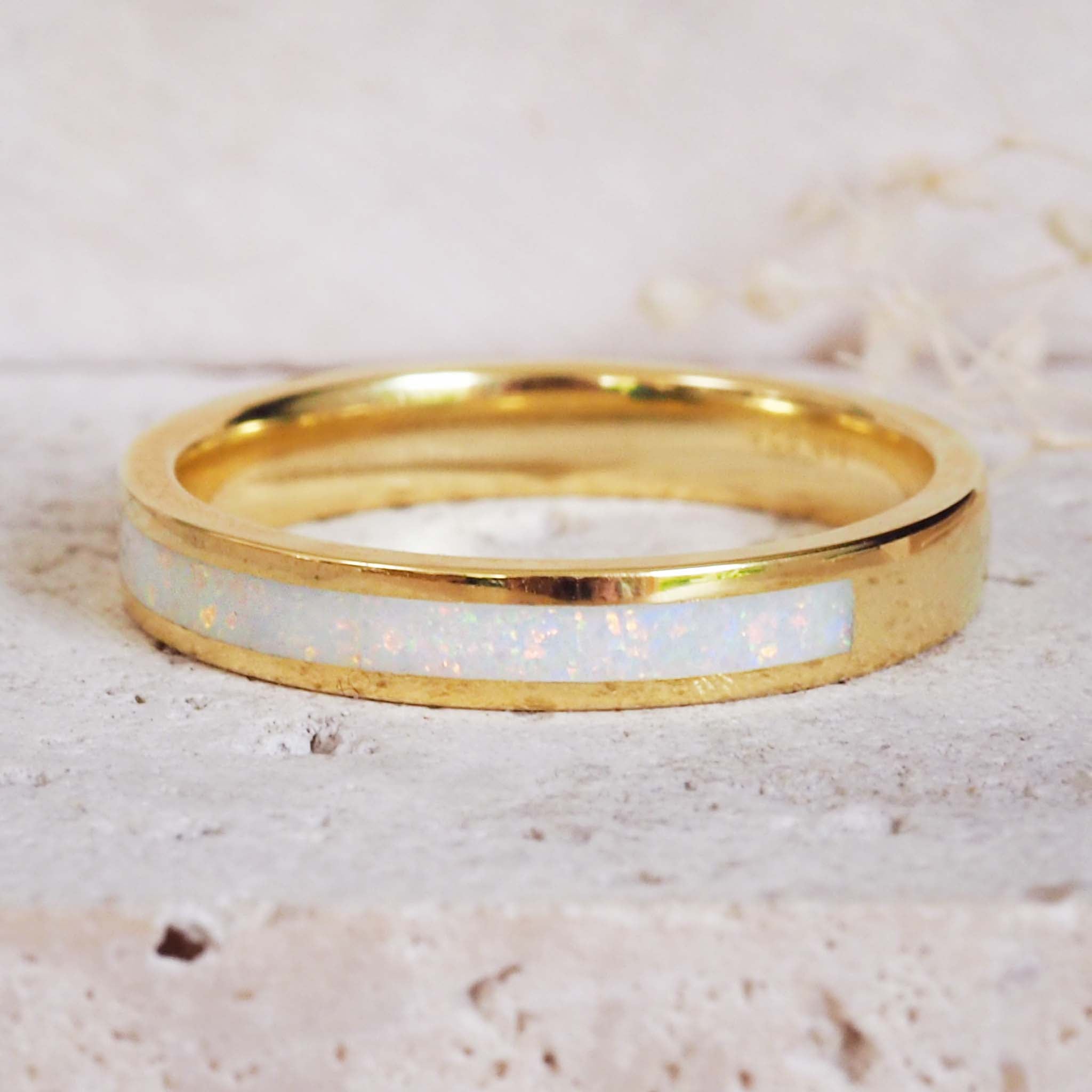 Gold ring with a white opal inlay on a light background