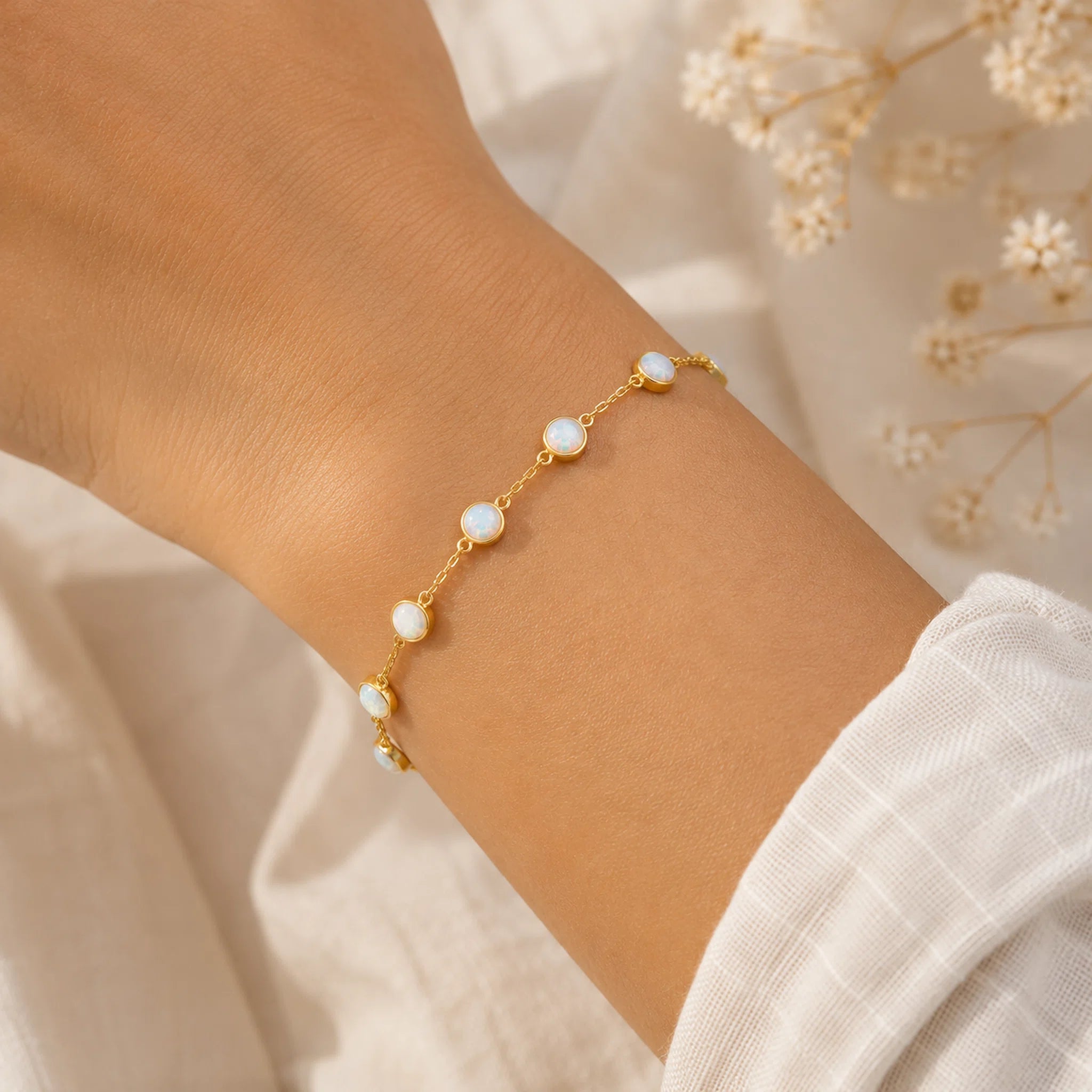 wrist wearing a gold chain bracelet with bezel set white opal stones
