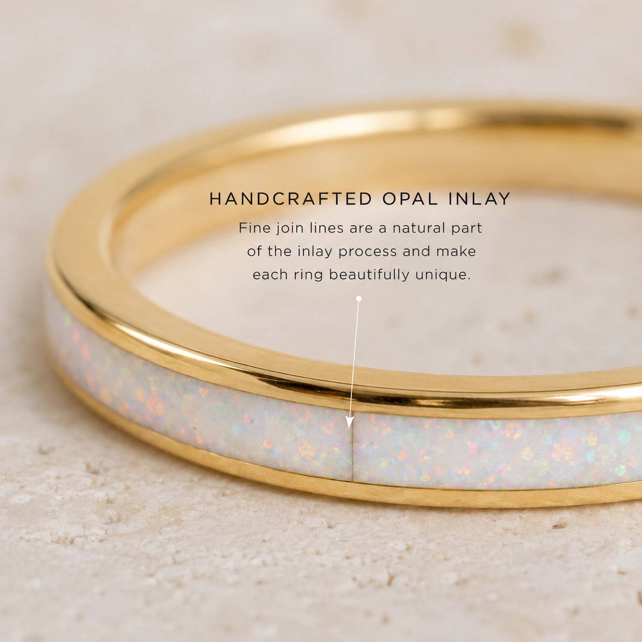 Gold ring with opal inlay on a beige background