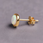 Gold White Opal stud earring on a grey background