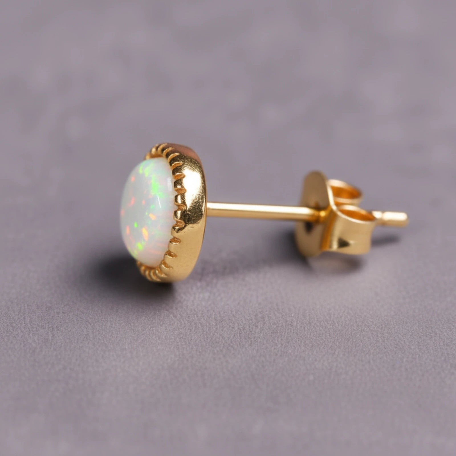 Gold White Opal stud earring on a grey background