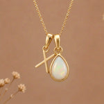 Gold Initial X Pendant and October birthstone Natural Opal Necklace against a warm background