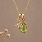 Gold Initial X Pendant and August birthstone Natural Peridot Necklace against a warm background