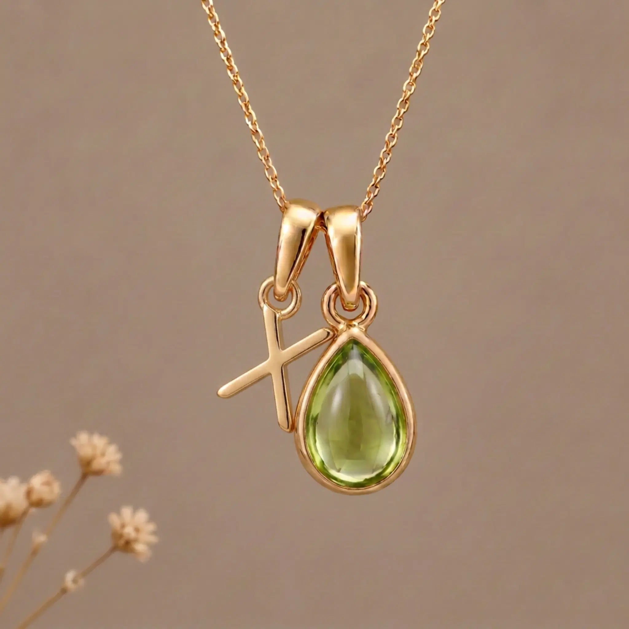 Gold Initial X Pendant and August birthstone Natural Peridot Necklace against a warm background