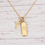 Gold Initial Y Pendant and Cancer Zodiac Pendant Necklace on a fine gold chain against a light wooden background