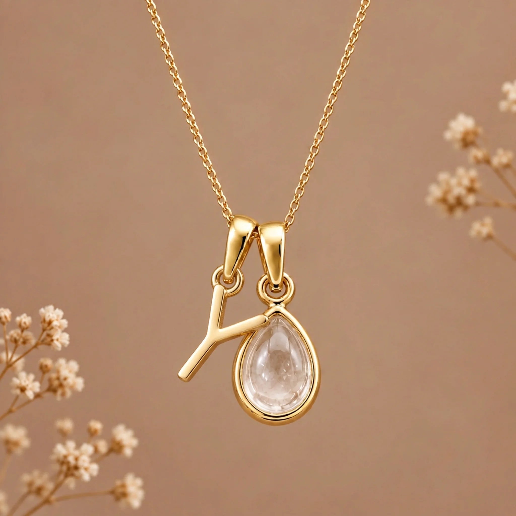 Gold initial Y necklace with an April clear quartz teardrop on brown with dried flowers