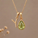 Gold Initial Y Pendant and August birthstone Natural Peridot Necklace against a warm background