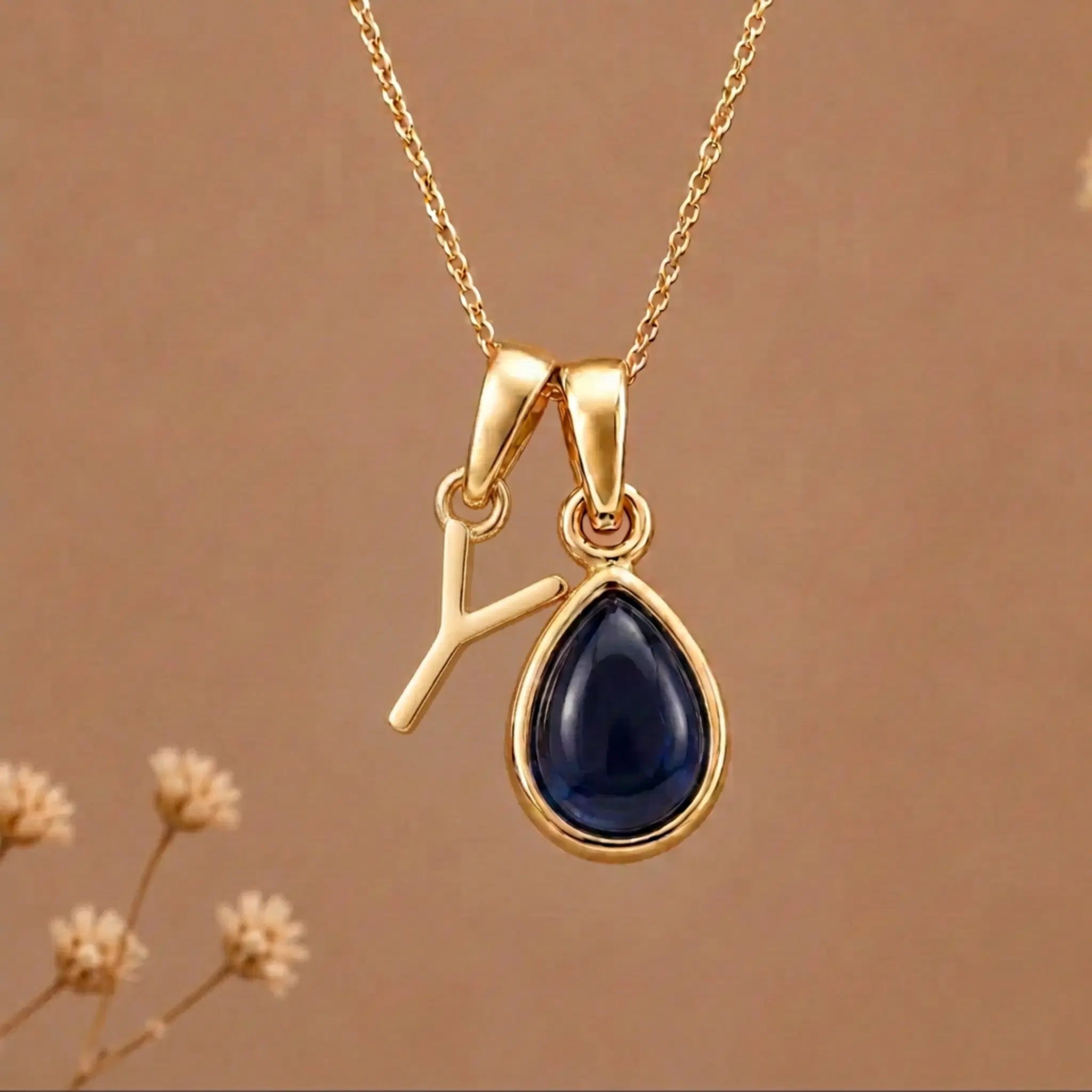 Gold Initial Y Pendant and September birthstone Natural Sapphire Necklace against a warm background