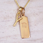 Gold Y Initial and Virgo Necklace on a fine gold chain against a light wooden background