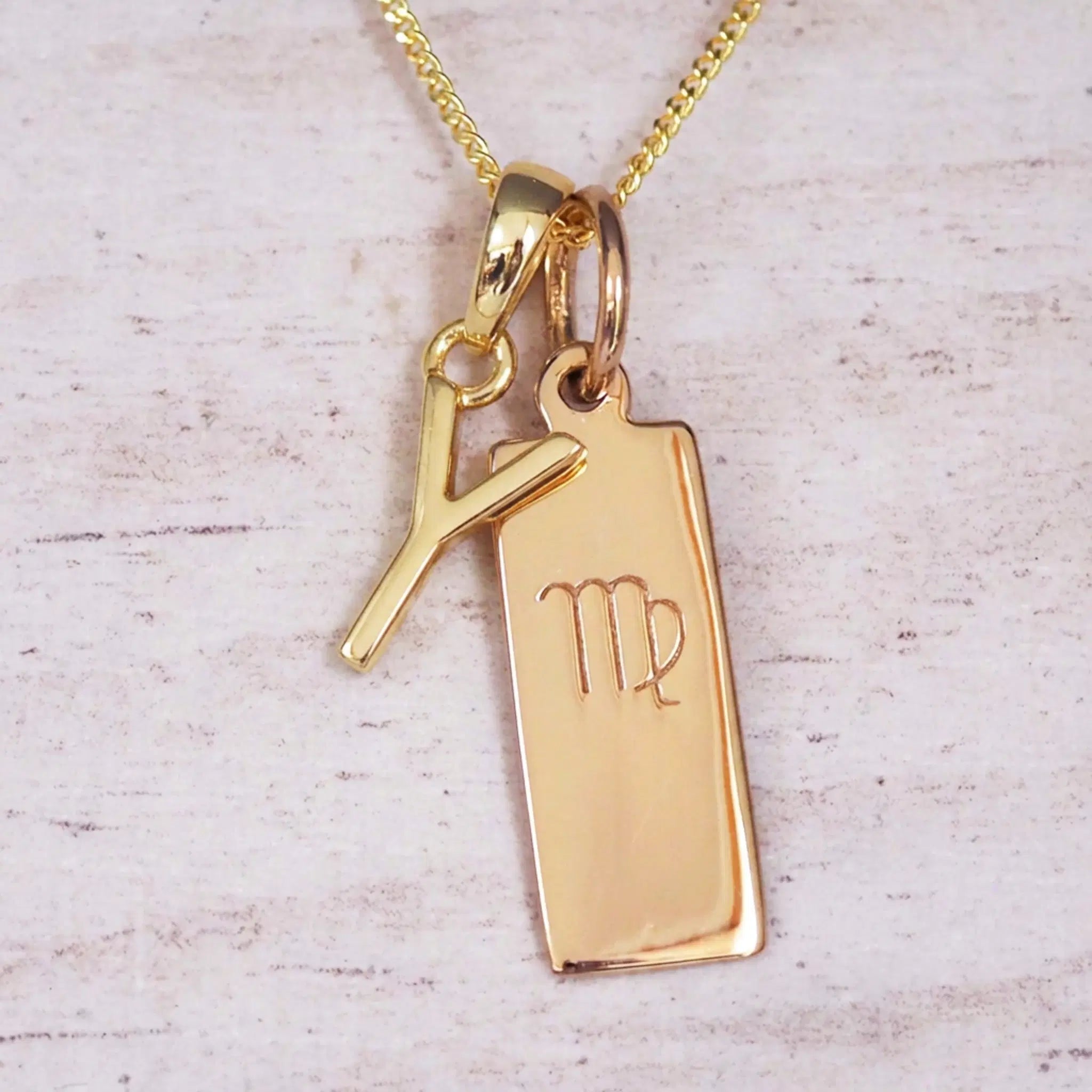 Gold Y Initial and Virgo Necklace on a fine gold chain against a light wooden background