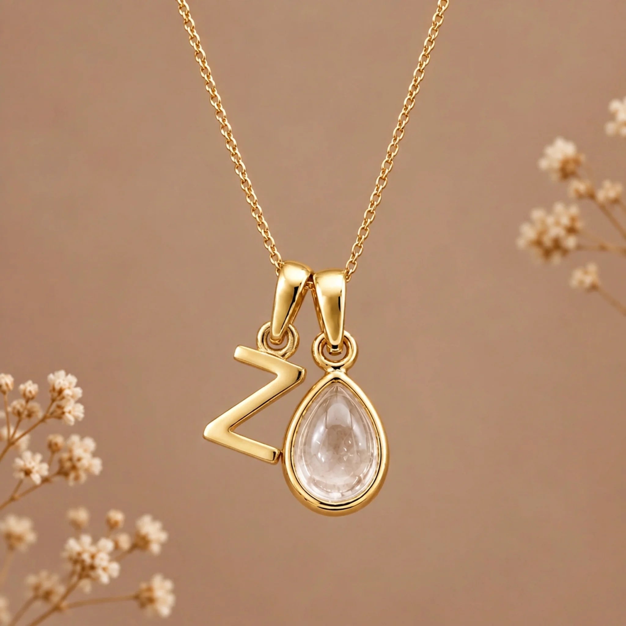 Gold initial Z necklace with an April clear quartz teardrop on brown with dried flowers
