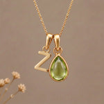 Gold Initial Z Pendant and August birthstone Natural Peridot Necklace against a warm background