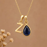 Gold Initial Z Pendant and September birthstone Natural Sapphire Necklace against a warm background