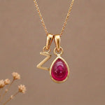 Gold Initial Z Pendant and July birthstone Natural Ruby Necklace against a warm background