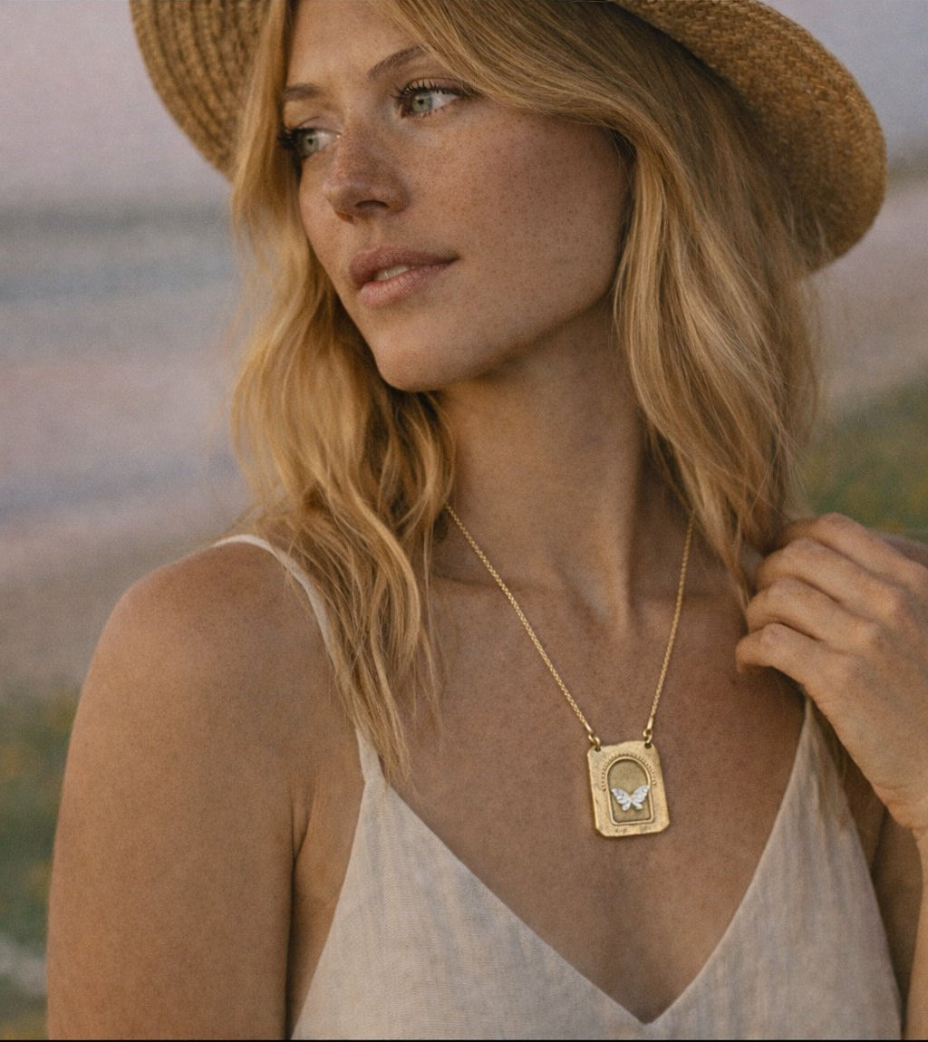 Woman wearing a gold necklace with a butterfly on it at the beach