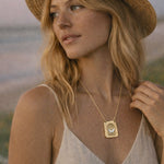 Woman wearing a gold necklace with a butterfly on it at the beach