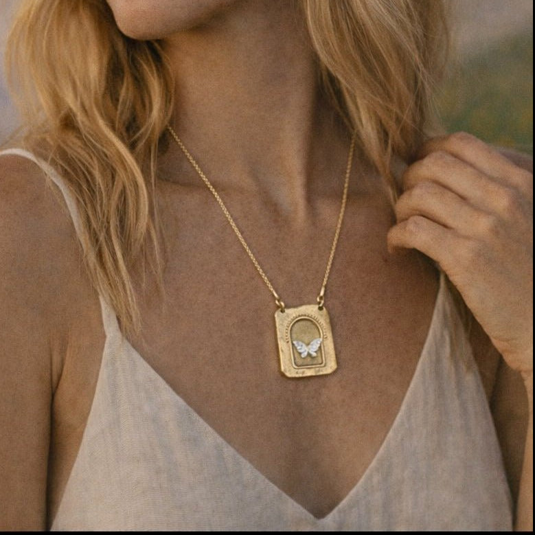 Woman wearing a gold necklace with a butterfly on it at the beach