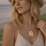 Woman wearing a gold necklace with a butterfly pendant outdoors