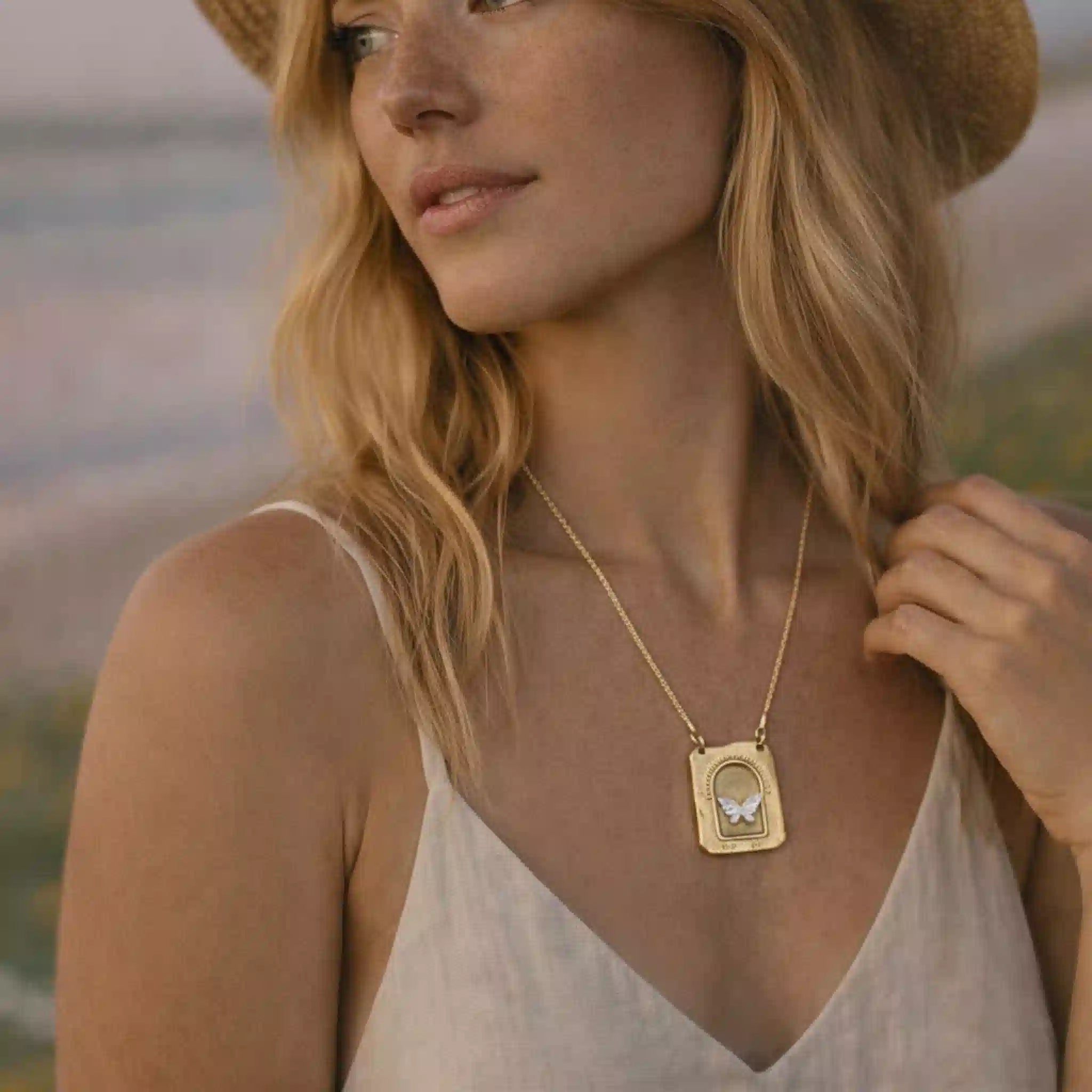 Woman wearing a gold necklace with a butterfly pendant outdoors