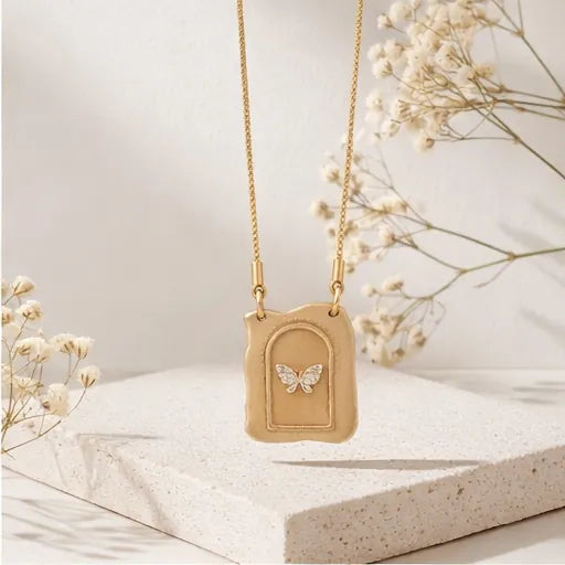Gold necklace with a butterfly pendant on a light background