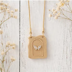Necklace with a beige pendant featuring a butterfly design on a light wooden background.