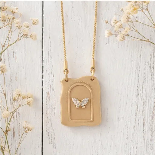 Necklace with a beige pendant featuring a butterfly design on a light wooden background.