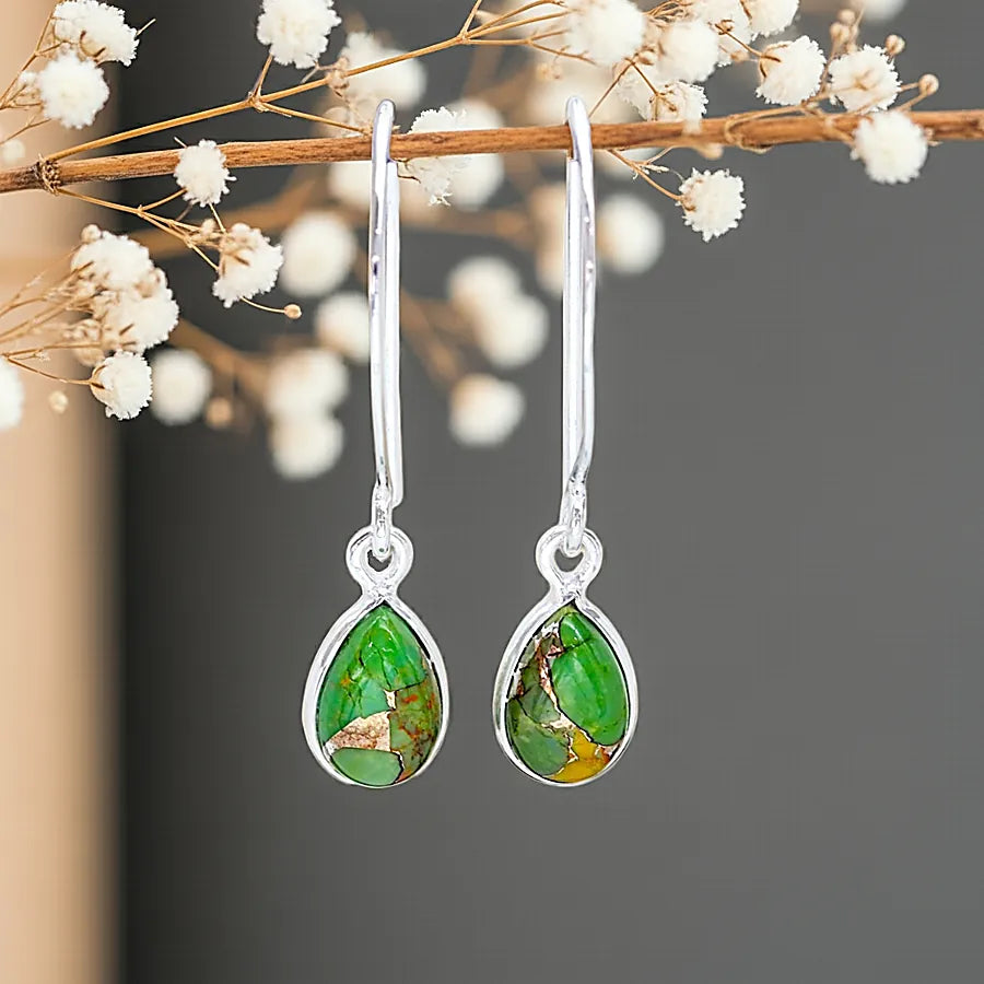 Green teardrop earrings with silver hooks on a branch with white flowers.