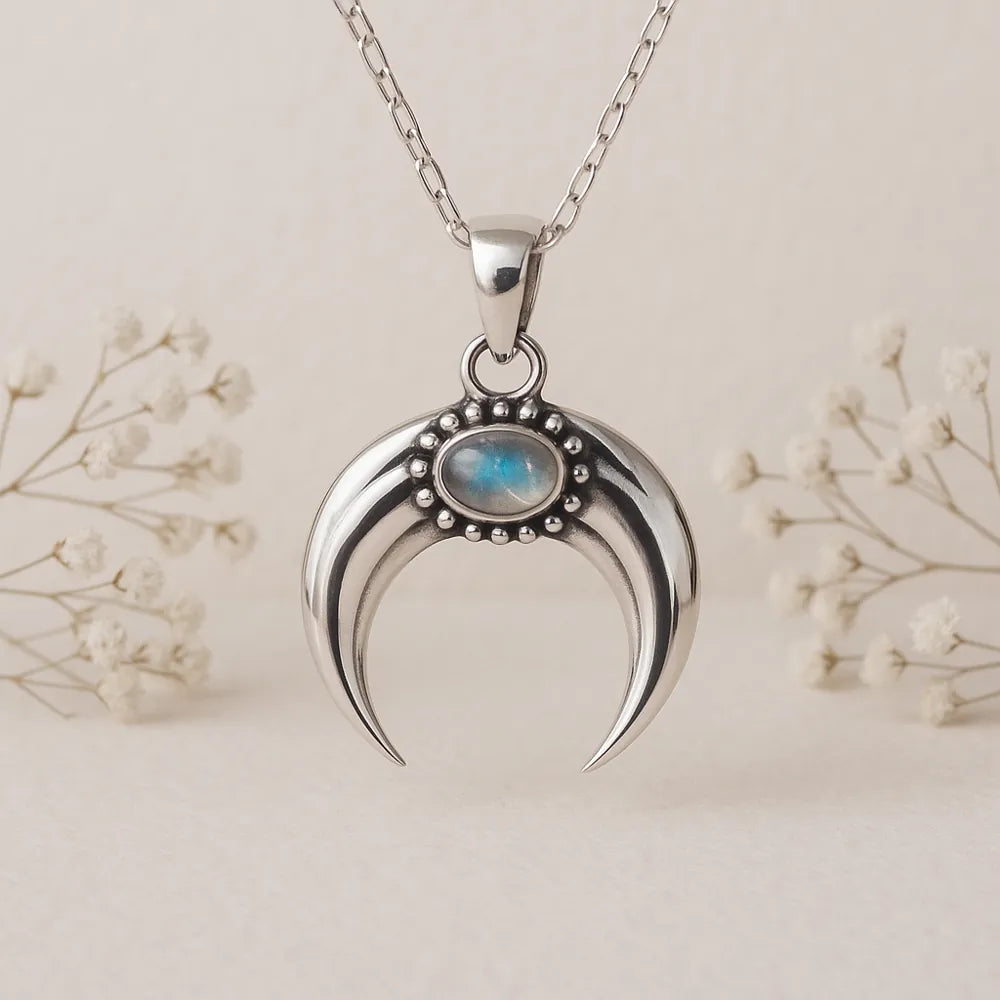 Silver crescent moon pendant with moonstone gemstone on a silver chain against a light background
