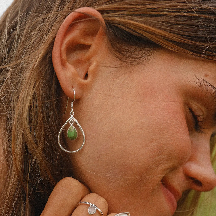 woman wearing teardrop shaped drop earring with smaller teardrop green turquoise stone in the middle