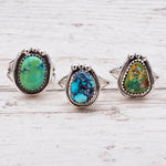 Navajo sterling silver turquoise rings on a light wooden surface, side view