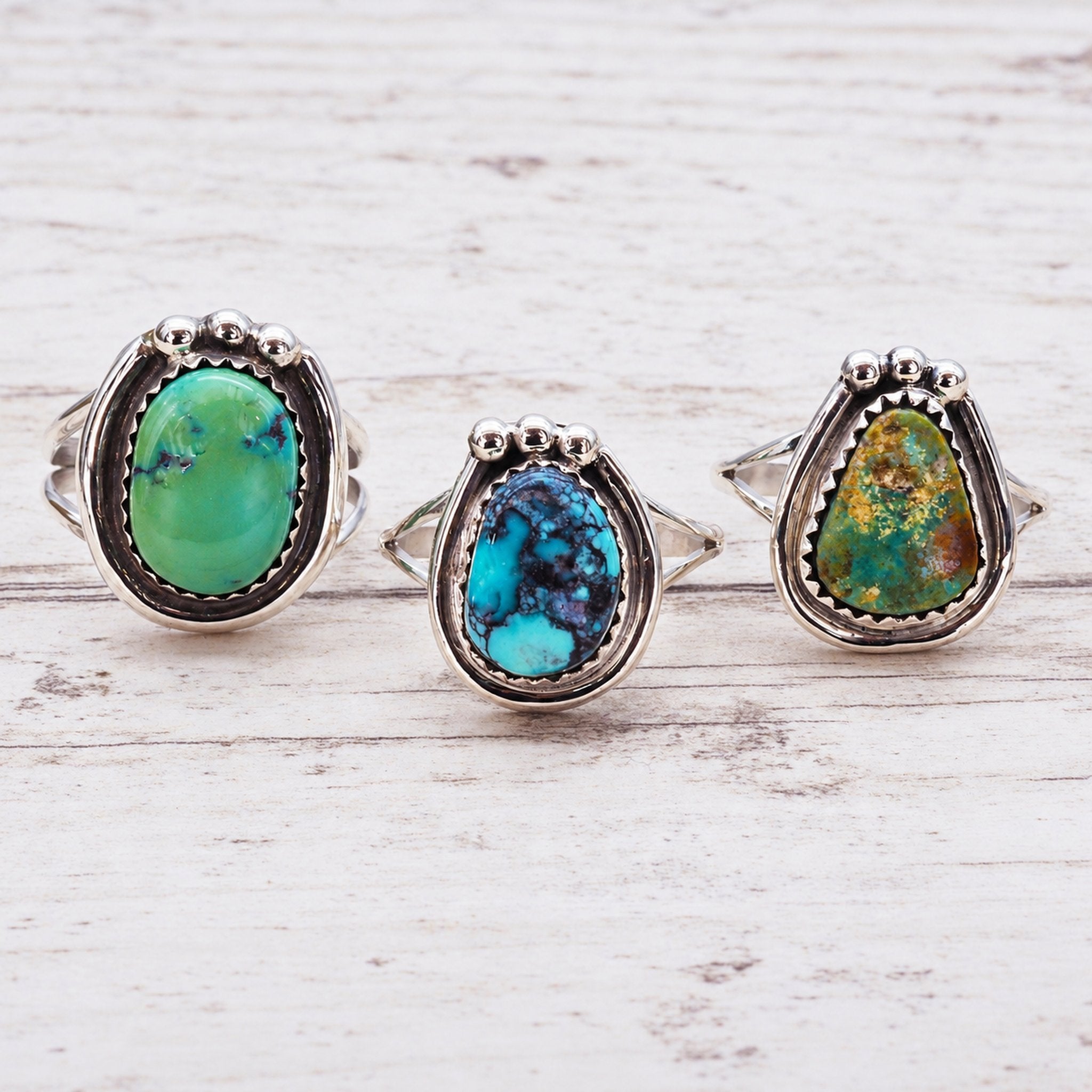 Navajo sterling silver turquoise rings on a light wooden surface, side view
