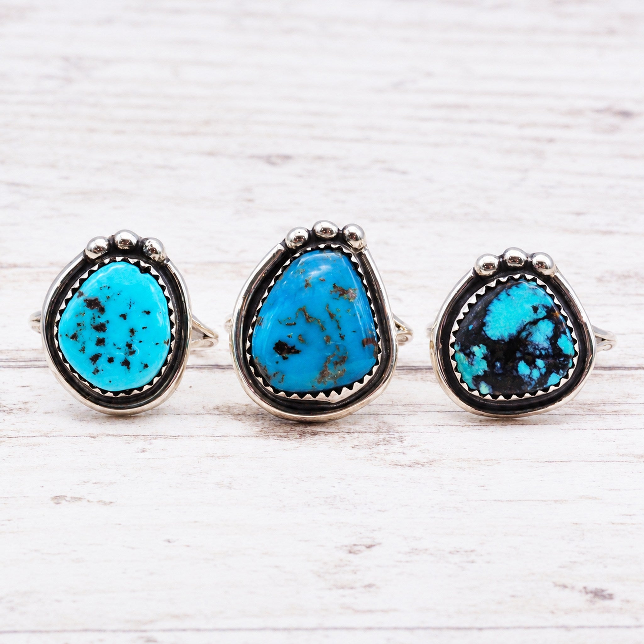 Navajo sterling silver turquoise rings on a light wooden surface