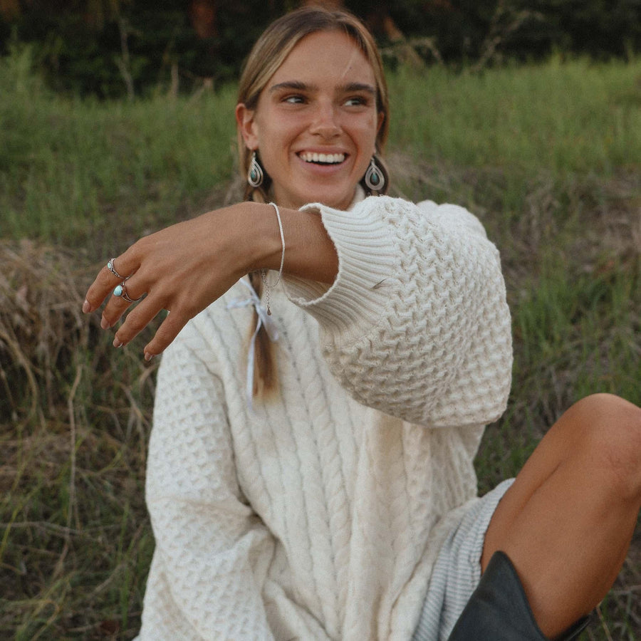Smiling woman wearing white woollen jumper and Sterling Silver Bracelet - Sterling silver jewellery australia