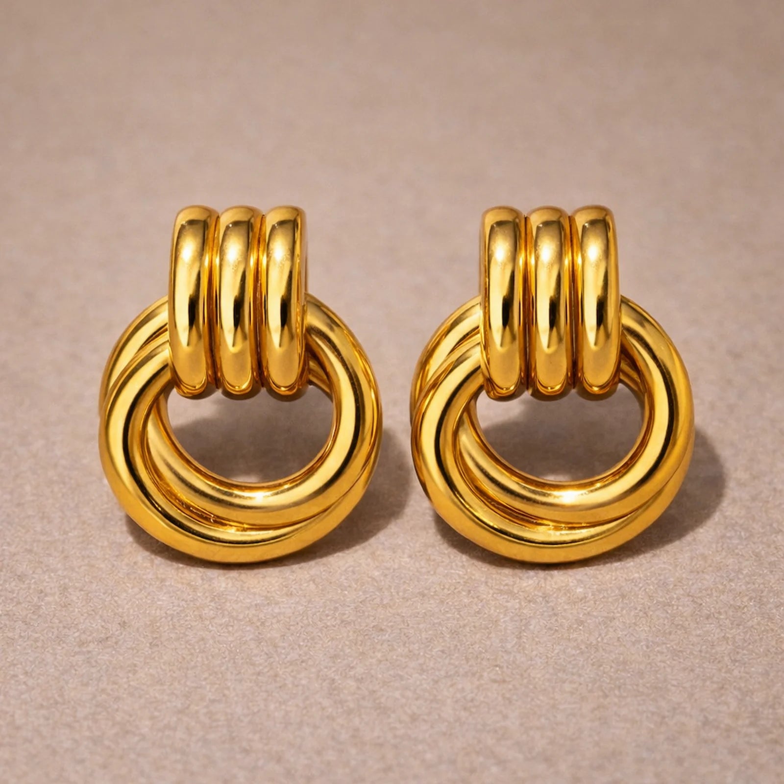 Pair of gold hoop earrings on a beige background